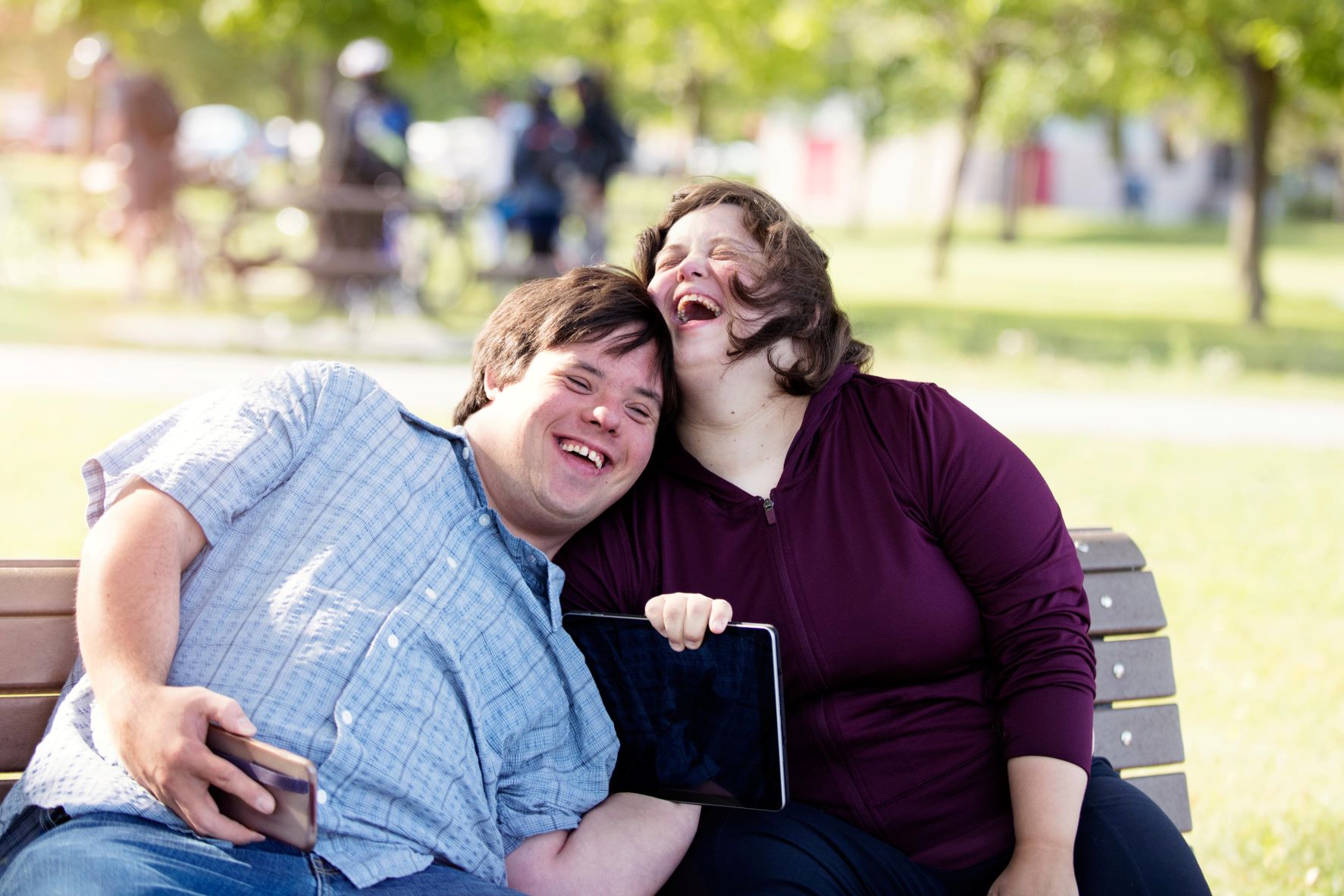 Två personer sitter på en parkbänk och skrattar